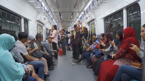 JAKARTA, Indonesia - March 26, 2019: Passengers using mobile phone in Mass Rapid Transit (MRT) subway train Jakarta. Shot in 4k resolution
