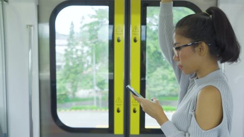 Young woman using a mobile phone while standing near the door in Jakarta MRT (Mass Rapid Transit). Shot in 4k resolution