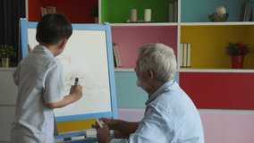 grandfather or senior man and grandson drawing picture art with senior man together with smiling and happy in living room as slow-motion background