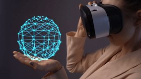 Young woman using a virtual reality headset with hologram structure and conceptual network lines. Woman holds in her hand a structural ball that rotates and expands