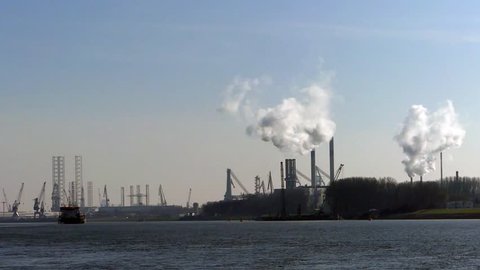 Europoort, Rotterdam, the Netherlands - March 28 2019: Industrial zone, equipment of oil and petro chemical refining, view at distance with chimney stacks pumping steam or smoke