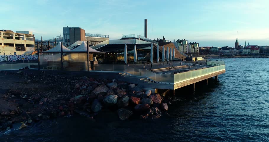 Smooth cinematic architecture aerial view of wooden building Löyly, Loyly during sunrise. Drone flying forward close to building dolly alike shot. Spring sunny morning. Helsinki Finland.