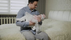 Young dad cradles a little girl on a bed.