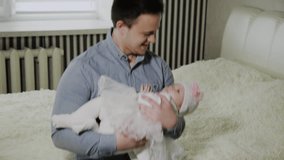 Young dad cradles a little girl on a bed.