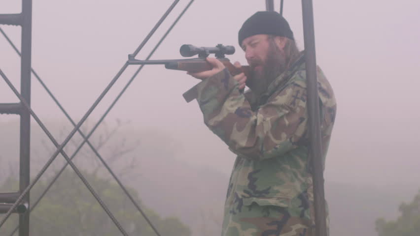 Man holding gun, looking through scope through the mist