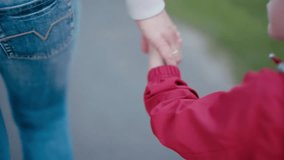 Close Up Shot on Parent and Child Hands: Mother is Leading Blond 4 year old Little Son Boy by Hand in the Park. Back View on Mom and Son Walking