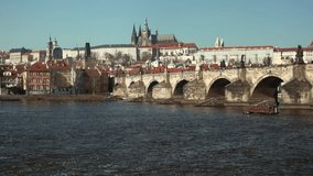 Prague - January 2019: Prague city view of Charles Bridge and boat on river with castle and St. Vitus cathedral in background. 4K resolution 