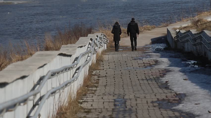 a couple in love a man and a woman go down together during a walk down the embankment on the river Bank on a spring Sunny day