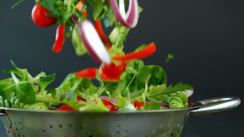 Fresh salad flying to colander in super slow motion.