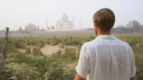 Young man traveling in India framing Taj Mahal with hands and fingers. male discovering India and sightseeing frames temples with hands- Slow motion 