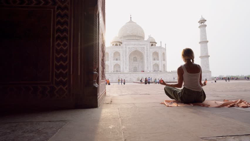 Young woman practicing yoga in India at the famous Taj Mahal at sunrise - People travel spirituality zen like concept - Girl doing yoga 