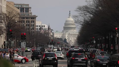 Washington, D.C. / USA - March 30, 2019: Cars and pedestrians create commuter traffic on a busy spring day on Pennsylvania Avenue with a view of the US Capitol building in the distance.