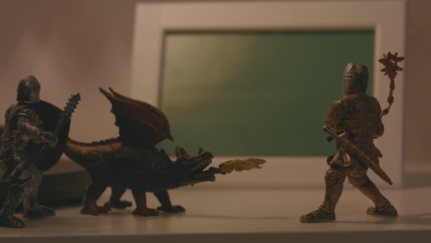 Close-up of three small figures of two knights and one dragon on a table