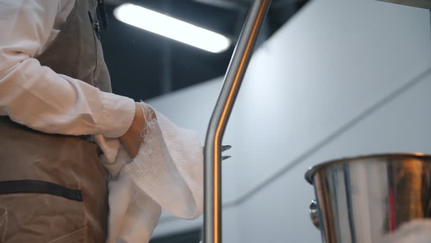 Close-up of kitchen worker in a white apron wiping spoons in a cafe or restaurant. Stock footage. The restaurant area