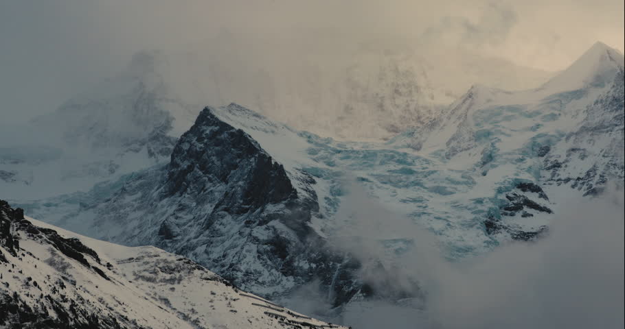 Timelapse of the mountains in Wengen, Switzerland during golden hour, with clouds covering the mountains.
