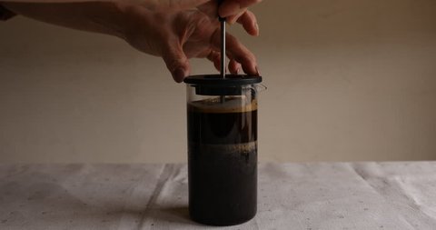 Pressing plunger down in french press to make coffee