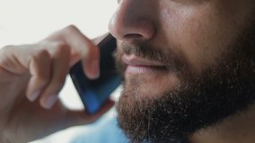 Close up shot of smiling bearded man talking on smartphone. Focus on lips. Communication and technology concept