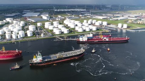 Aerial view of busy harbor area oil depot is an industrial facility for storage of petrochemical products showing tankers and tugs maneuvering the congested port waters 4k high resolution footage