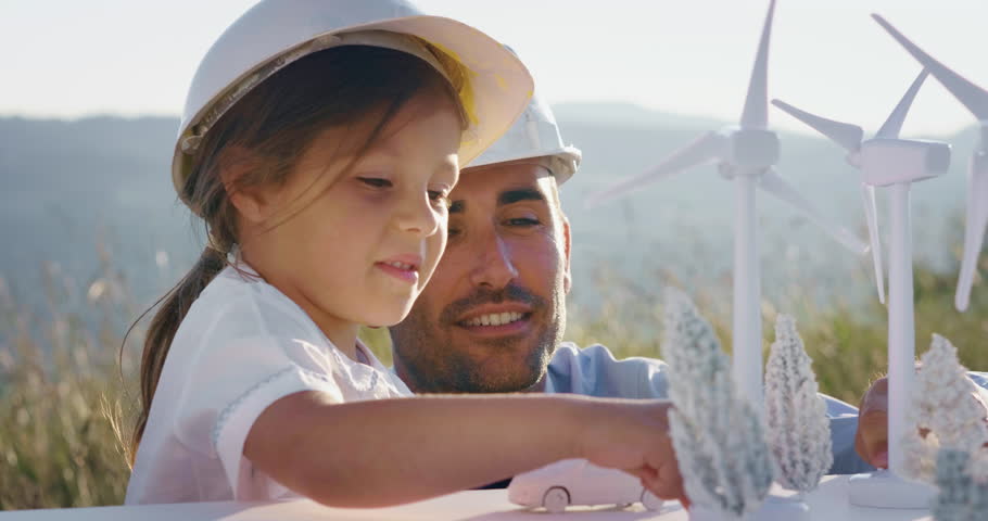 A father engineer shows his project to his daughter for the construction of a wind farm. The daughter is interested in renewable energy. Concept of: family, engineering, future love for nature. Royalty-Free Stock Footage #1026694994