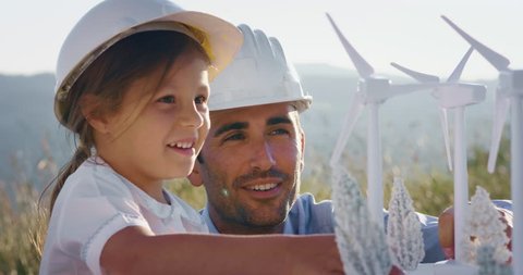 A father engineer shows his project to his daughter for the construction of a wind farm. The daughter is interested in renewable energy. Concept of: family, engineering, future love for nature.