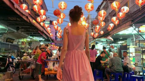 Bangkok, Thailand - 03 February 2019: tourist girl in a striped pink dress is walking through the crowd on the asian street market during the celebration of Lunar New Year. Video recording. Editorial.