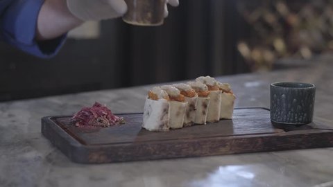 Chef cooking tasty dish in modern restaurant close up. Man sprinkling lula kebab in lavash pita rolls with seasoning looking at the food attentively. Turkish cuisine
