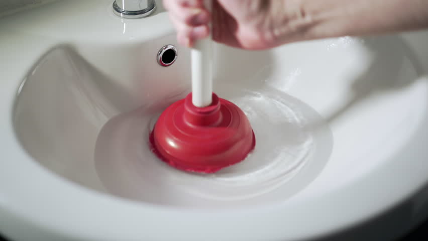 Red and white plunger unblocking white wash hand basin sink, mans hand. Royalty-Free Stock Footage #1026723848