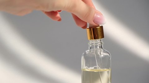 Dropper glass Bottle Mock-Up. Oily drop falls from cosmetic pipette on white background. 