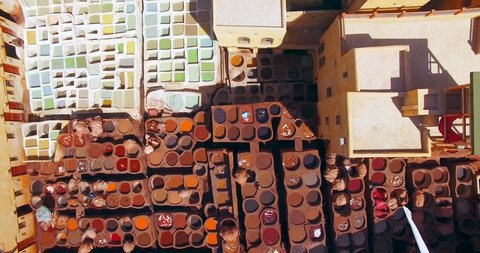 FEZ, MOROCCO. Top aerial drone 4K view over little stone pools kaleidoscope within the Tanners Quarter. Workers dye skins and hides in the shades of red, blue, brown, green and yellow.