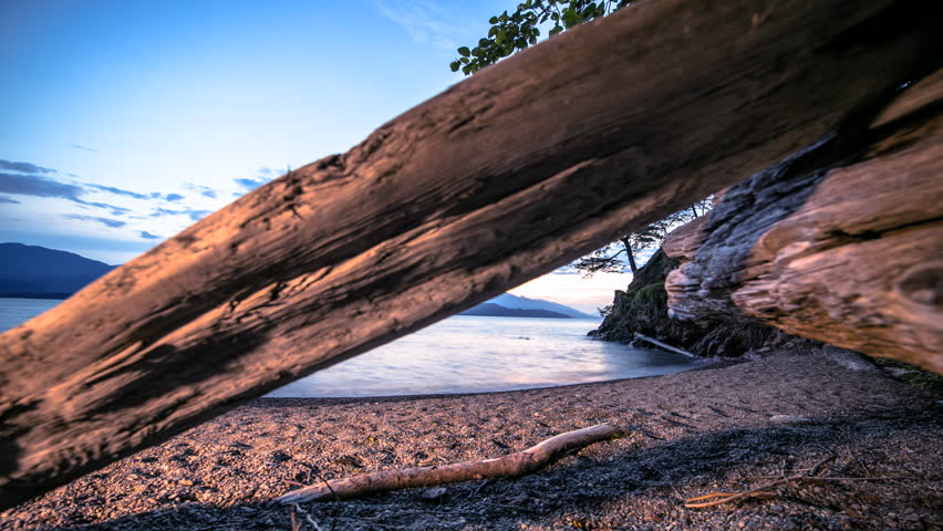 Timelapse of Sunset Under Moving Beach Logs