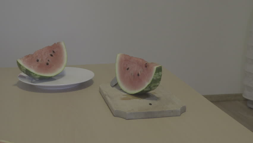 Male hands slicing watermelon in neutral house environment