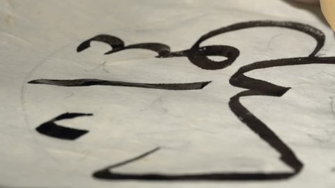 calligrapher writes arabic lettering with calligraphy pen on parchment. macro shot of islamic calligraphy art. close up slider dolly shot in calligrapher workshop. hand made calligraphy