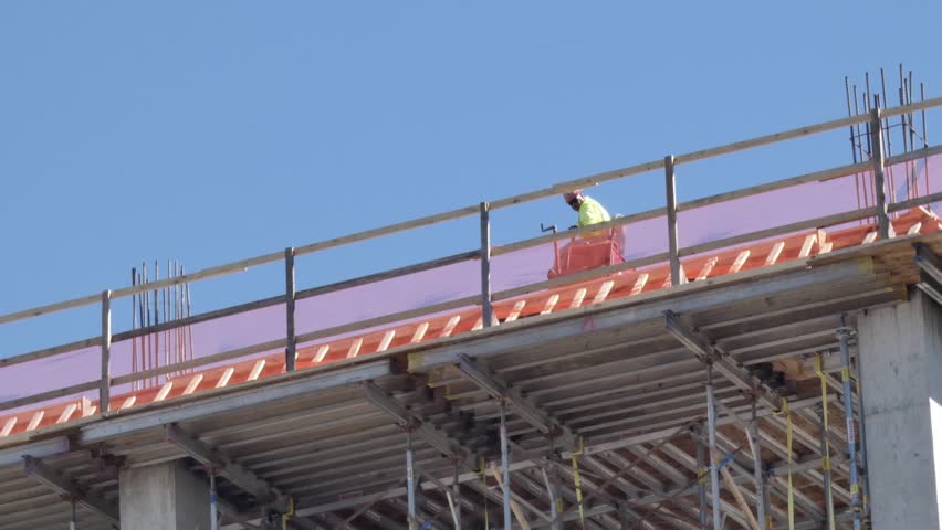 man on machine working on top of building being built on construction site
