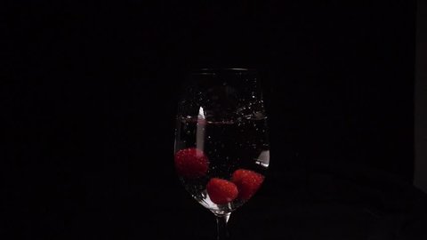 Raspberries fall into a glass in slow motion. Food video