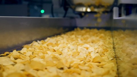 Sorted chips moving on a factory line in a food facility, slow motion.