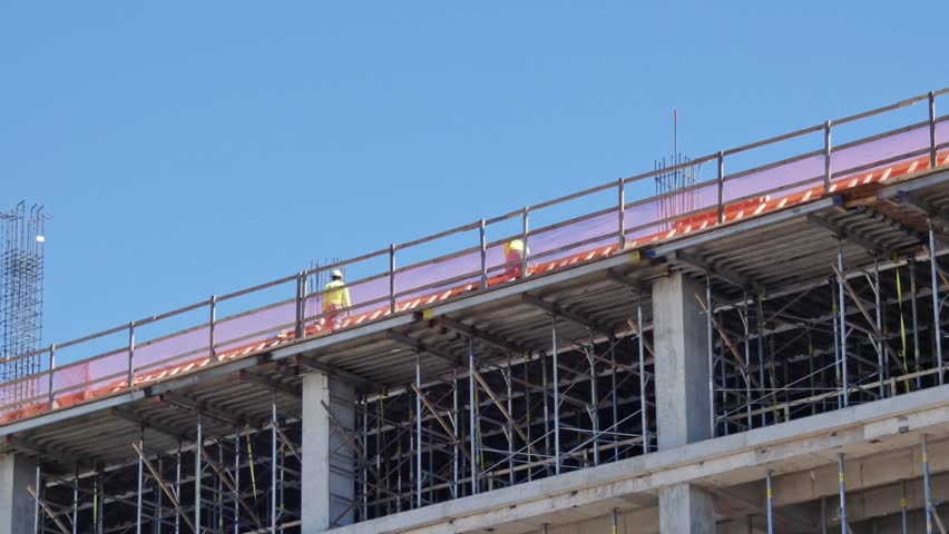 Tow men working on top of a building being built on construction site