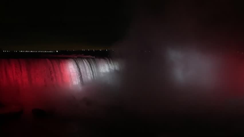 Footage video of illuminated glowing red and white Niagara Falls at night, filmed  from Canadian side. Horseshoe Falls, Canada, Ontario.