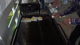 FOUNTAIN GREEN, UTAH - JUL 2014: Cooking eggs outdoor iron grill. Cooking eggs on cast iron camping grill outside. Outdoor breakfast picnic white and yellow eggs. 4K video.