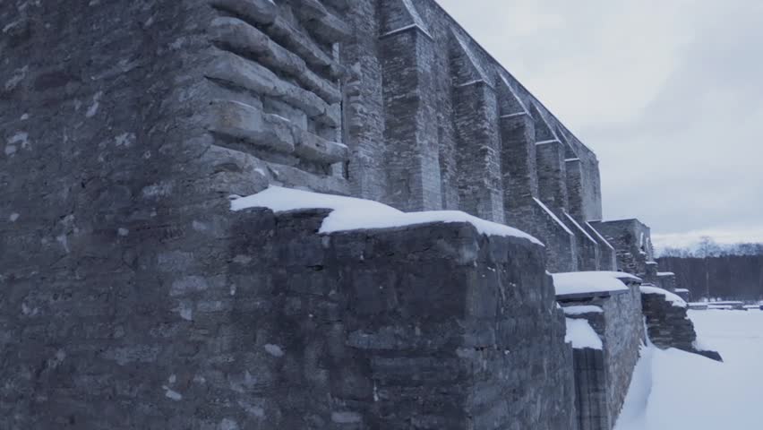 Stone wall in ancient covent ruins covered in snow during overcast day, tracking right shot