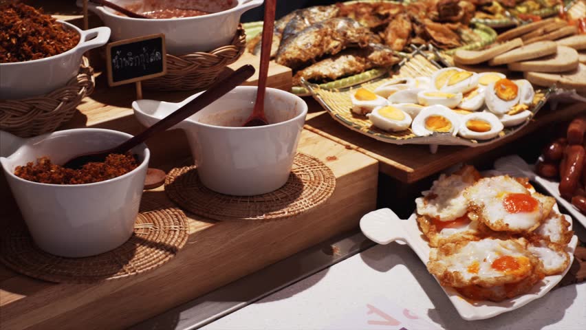 Different meal in Bangkok food court: fried fish, boiled and fried eggs, grilled sausages, sauce, porridge, bread, seafood. Thailand
