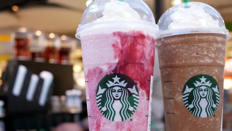 Burnaby, BC, Canada - March 26, 2019 : Motion of frappuccino beverage on table with blurred worker cleaning on table inside Starbucks store with 4k resolution.