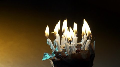 Close up of lots of candles in a cup cake being blown out.