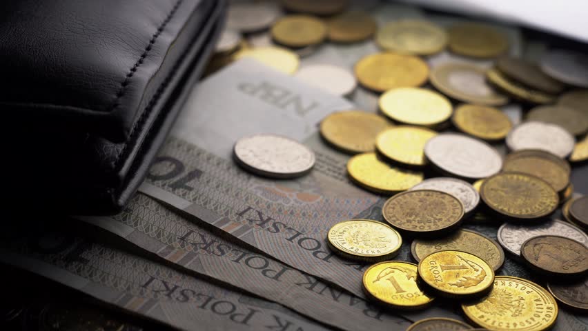 Slow pan to the left of some polish money ( Zloty ) with a wallet in top of a table.
