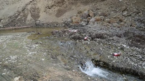 Miercurea Ciuc, Romania- 01 April 2019: Small clean creek polluted with plastic beer bottles, conceptual footage of human negligence.