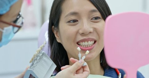 Woman check the color of the teeth for whitening at dental clinic