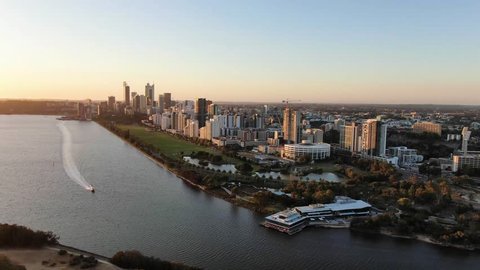 Beautiful evening aerial drone footage of the city of Perth, Western Australia, right before sunset. Speed boad on the river in the foreground and Langley park behind. Perth is the capital city of WA.