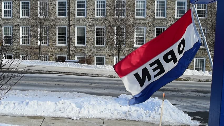 business open sign flapping with brick building and cars driving by