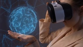 Young woman using a virtual reality headset with hologram structure and conceptual network lines. Woman holds in her hand a rotating structural ball