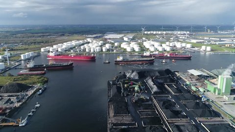 Aerial arriving at of busy harbor area oil depot is an industrial facility for storage of petrochemical products showing tankers and tugs maneuvering the congested port waters 4k high resolution