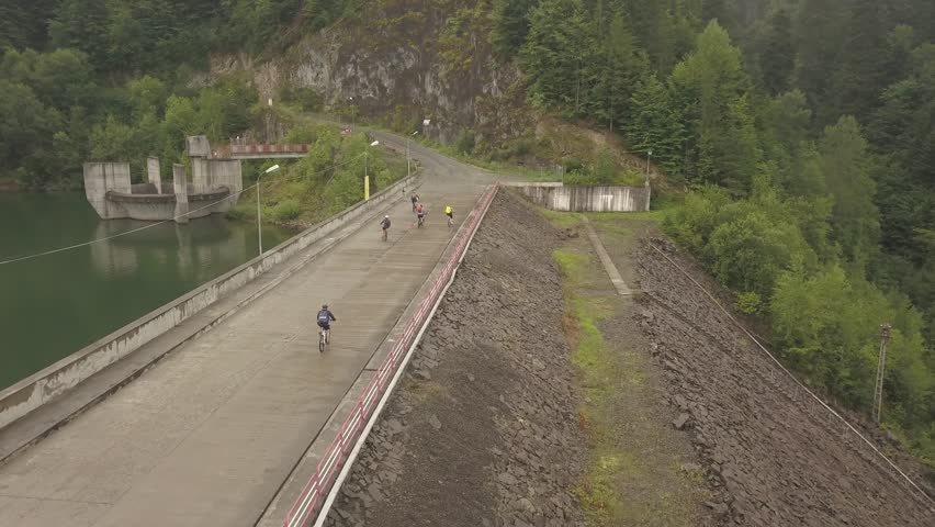 Aerial view of a group of bicyclist biking in the dam at Colibita Lake in Romania during Tura Cu Copaci race.